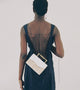 Editorial image of rectangular, structured bag with golden art deco-inspired top handles. White and raffia coloured summer bag.