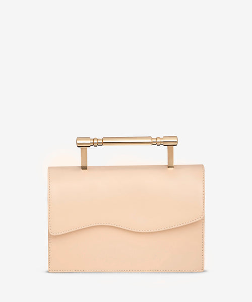 front view of luxury creme structured bag with gold top handle, featuring Mashu's signature wavy design on the front flap
