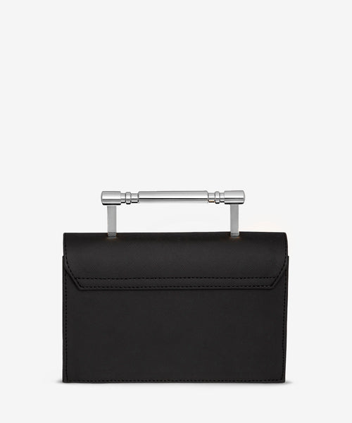 Chic black Saffiano leather handbag with a striking silver Art Deco top handle, blending modern luxury with vintage-inspired design for a standout look.