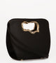 A minimalist, black leather handbag with a sculptural gold-tone handle opening, featuring an asymmetrical organic design, side view.