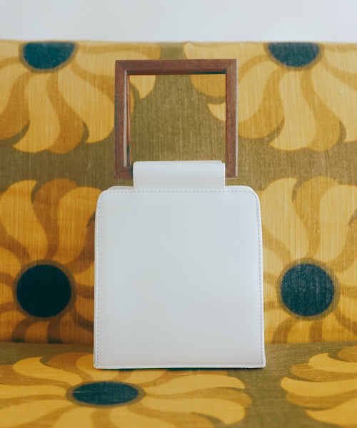 Editorial photo of a luxury handbag made from plant-based materials with wooden, re-purposed square handles