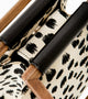 A contemporary handbag with a beige and black spotted pattern, a square wooden top handle, and a sleek black leather attachment.