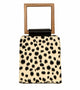 A modern animal-print handbag with a structured silhouette, black brushstroke-style spots, and a square wooden handle with a black leather accent.