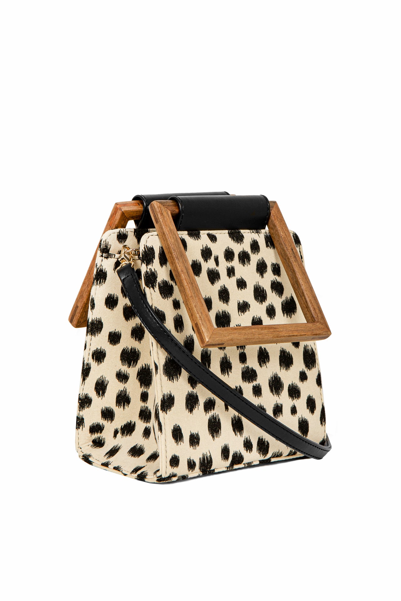 A modern animal-print handbag with a structured silhouette, black brushstroke-style spots, and a square wooden handle with a black leather accent.