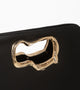 A minimalist, black leather handbag with a sculptural gold-tone handle opening, featuring an asymmetrical organic design.