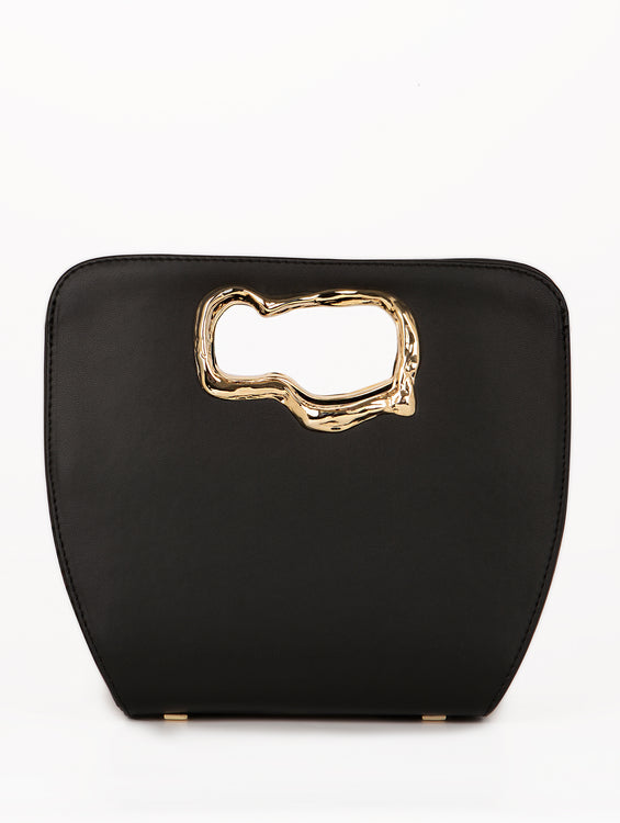 A minimalist, black leather handbag with a sculptural gold-tone handle opening, featuring an asymmetrical organic design.