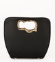 A minimalist, black leather handbag with a sculptural gold-tone handle opening, featuring an asymmetrical organic design.