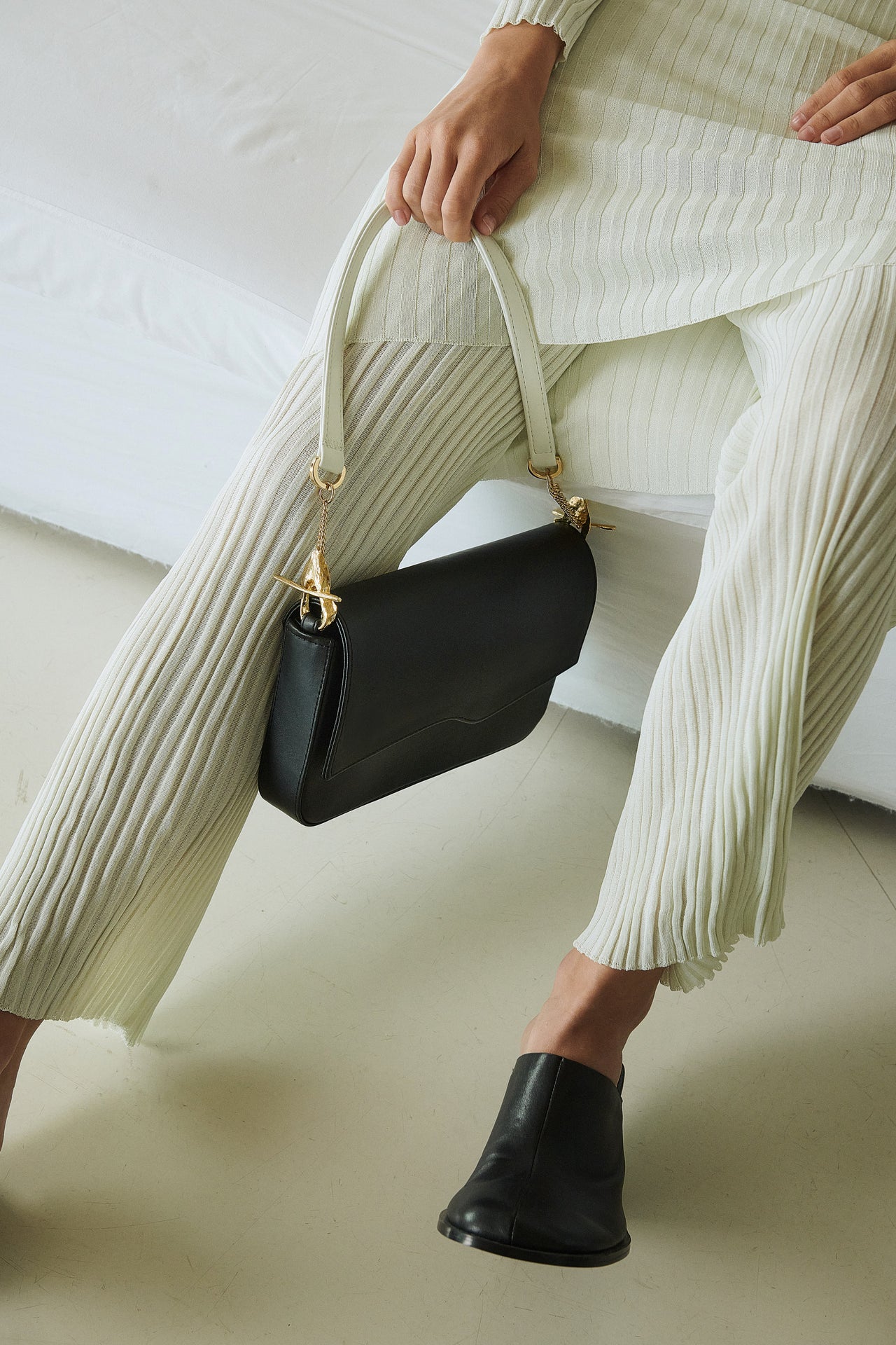 Chic black shoulder bag featuring unique gold hardware and contrasting white handles, blending modern elegance with timeless sophistication.